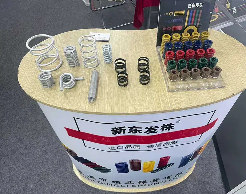 Colorful compression springs and mold springs display at Dili Spring PTC ASIA booth showing JIS and US standard springs
