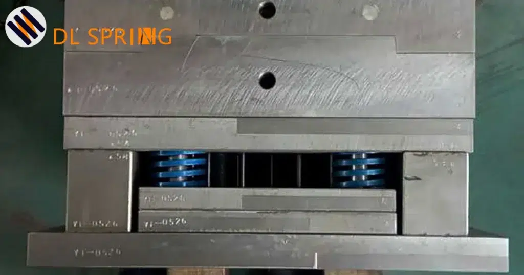Blue JIS standard mold spring installed in injection mold showing YI-HSZH marking and coating