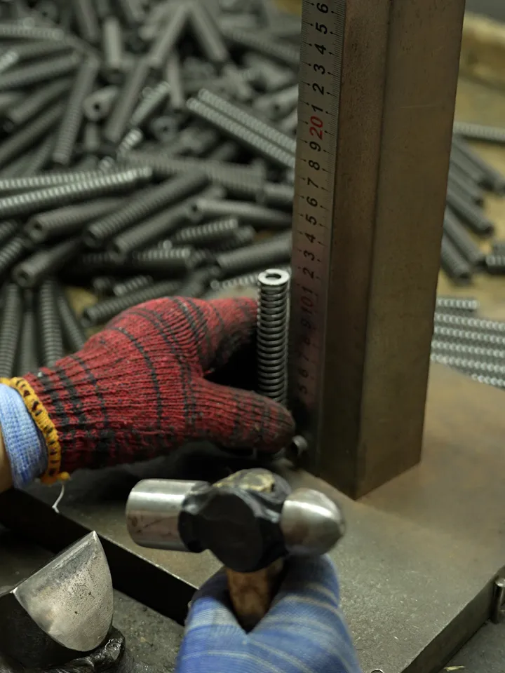 Quality inspector measuring spring dimensions using precision calibrated instruments during correction process