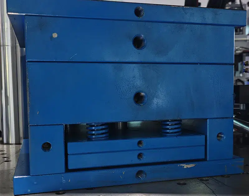 Close-up view of die spring installation in injection mold showing blue compression springs, ejector plate assembly, and precision machined spring pockets