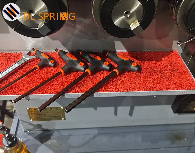 Precision tools neatly organized on red tray in spring manufacturing workshop showing quality control standards