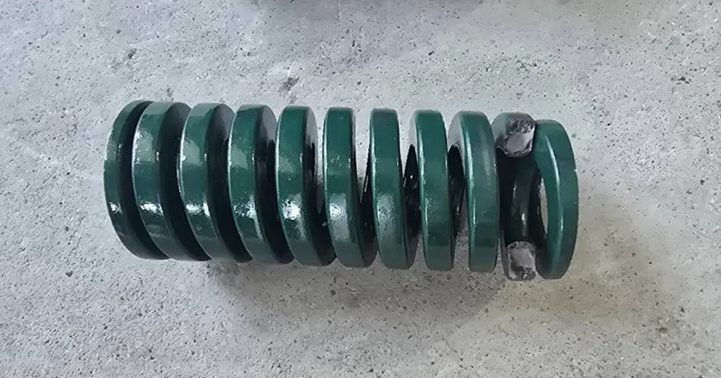Fractured die spring with broken end coils illustrating fatigue failure after exceeding rated cycle life